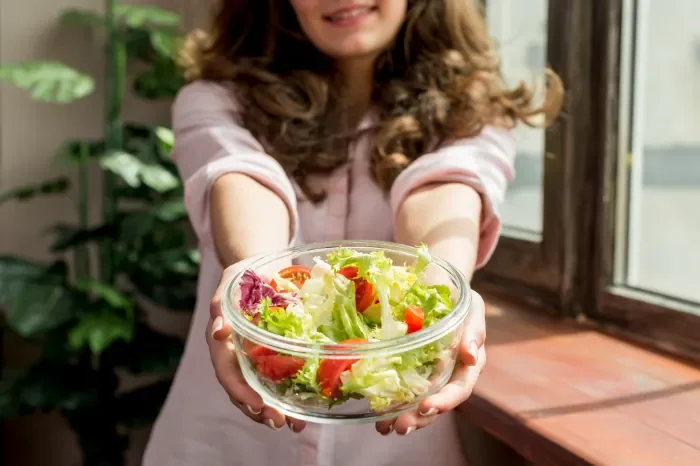 Mujer ofreciendo ensalada saludable